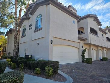 Ironwood Condominiums building with attached garages, landscaping, and brick driveway at 8309 Cherry Glaze Ave # 201, Las Vegas, NV 89145