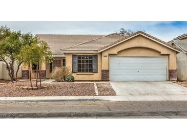 Tan one-story house with a white garage door and landscaped front yard at 5529 Cypress Creek St, North Las Vegas, NV 89031