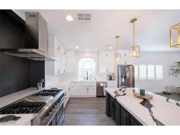 Modern kitchen features a stainless steel stove, marble countertops, an island, and a large window at 10658 Salmon Leap St, Las Vegas, NV 89183