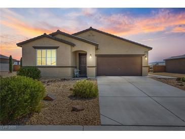 Charming single-story home featuring desert landscaping and a two-car garage at sunset at 3543 E Wallowa Dr, Pahrump, NV 89061