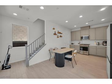 Bright kitchen features modern appliances, gray cabinets, and a dining area with stylish table and chairs at 655 Solar Citrine St, Las Vegas, NV 89138