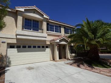Two-story house with a beige facade, attached garage, and palm trees at 6604 Octave Ave, Las Vegas, NV 89139