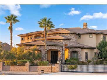 Elegant stone and stucco home featuring a gated entrance, palm trees, and well-manicured landscaping at 670 Du Fort Ave, Henderson, NV 89002
