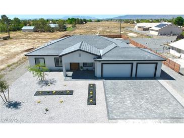 Stunning aerial view of a modern home with a gray tile roof, xeriscaped front yard, and paver driveway at 1691 Blackhorn St, Pahrump, NV 89048