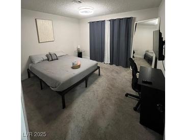 Cozy bedroom features a simple bed frame, grey carpet, and an adjacent desk area at 3625 Winner Dr, Las Vegas, NV 89120