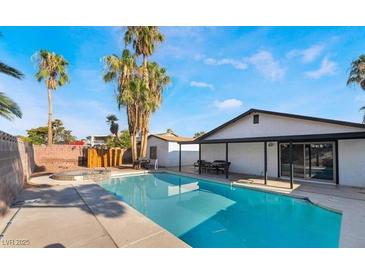 A backyard oasis with a sparkling pool, hot tub, palm trees, and covered patio at 3625 Winner Dr, Las Vegas, NV 89120