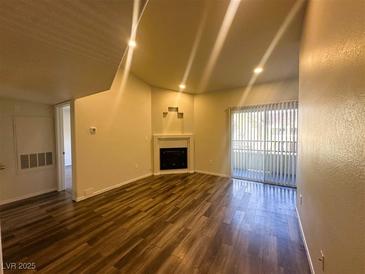 Bright living room with fireplace, wood floors, and sliding glass door to a balcony at , Henderson, NV 89014