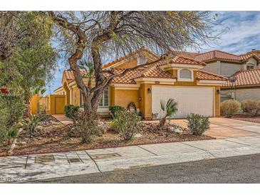 Charming single-story home with a well-manicured front yard and a two-car garage, complemented by lush landscaping at 1424 Desert Hills Dr, Las Vegas, NV 89117