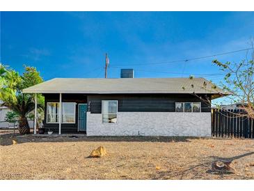 Ranch style home with dark gray siding, white rock accents, and a teal front door at 207 W Victory Rd, Henderson, NV 89015