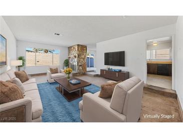 Bright living room features a stone fireplace, plush seating, and an open layout to the kitchen at 720 Sam Jonas Dr, Las Vegas, NV 89145