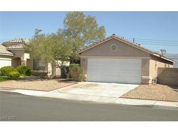 Beige single story home with low maintenance yard and white two car garage door at 108 Zenith Point Ave, North Las Vegas, NV 89032