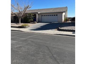 Single-story home featuring a well-maintained front yard and a two-car garage with stylish driveway at 117 Forest Ln, Boulder City, NV 89005