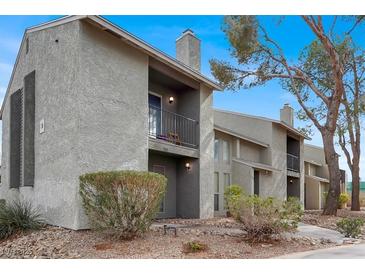 Two-story condo building showcasing a small balcony, chimney and desert landscaping at 584 Sellers Pl, Henderson, NV 89011