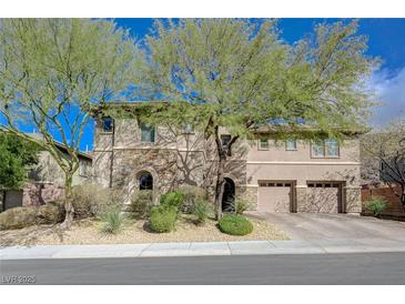 Charming two-story home featuring a combination of stone and stucco exterior, complemented by mature trees and a two-car garage at 2124 Pont National Dr, Henderson, NV 89044