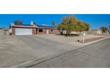 Charming single-story brick home featuring a two-car garage, solar panels, and low-maintenance landscaping at 4424 Shady Hollow Ave, North Las Vegas, NV 89031