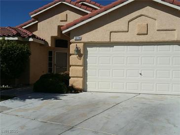 Tan house with tile roof, attached garage, and landscaping at 5018 Rio Linda Cir, North Las Vegas, NV 89031