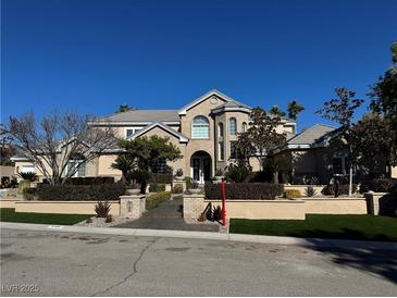 Elegant brick home featuring manicured landscaping and a symmetrical facade at 8100 Via Del Cerro Ct, Las Vegas, NV 89117