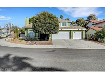 Two-story home featuring a three-car garage, mature tree in the front yard and green paint at 8908 Rocky Shore Dr, Las Vegas, NV 89117