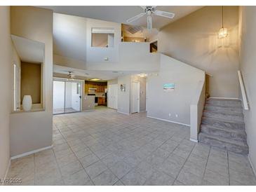 Bright living room features an open floor plan, stairs to the second floor, neutral paint and tile floors at 928 Allure Dr, Las Vegas, NV 89128