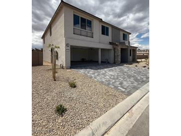 Two-story home with a gray brick driveway and a three-car garage in a modern style at 7199 Twilight Rider Ct, Las Vegas, NV 89118
