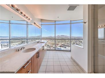 Bright bathroom with dual sinks, a glass shower, and expansive windows offering stunning city views at 200 W Sahara Ave # 2108, Las Vegas, NV 89102