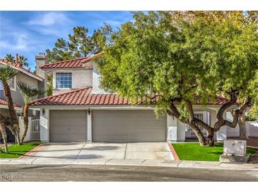 Charming two-story home featuring a tile roof, a two-car garage, and lush landscaping at 2921 Moonlight Bay Ln, Las Vegas, NV 89128