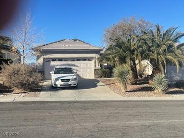 Charming single-story home featuring a two-car garage, desert landscaping, and mature palm trees in a sunny, residential neighborhood at 2341 Celestial Moon St, Henderson, NV 89044