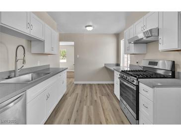 Updated kitchen features new stainless steel appliances, modern white cabinets, and beautiful countertops at 2716 Salt Lake St, North Las Vegas, NV 89030