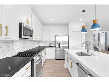Bright kitchen features white cabinetry, stainless steel appliances, a large island and pendant lighting at 12125 Arrebol Ave, Las Vegas, NV 89138