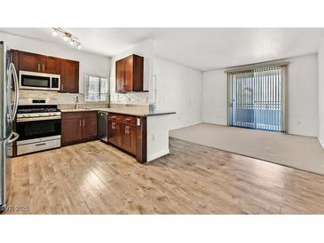 Bright kitchen featuring wood floors, stainless steel appliances, granite countertops, and breakfast bar at 1830 N Buffalo Dr # 2106, Las Vegas, NV 89128