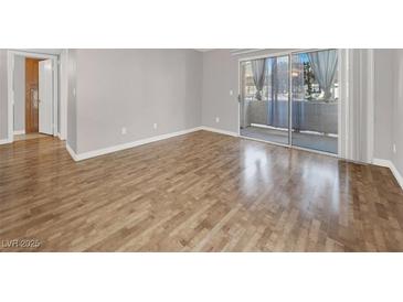 Bright living room with hardwood floors and sliding glass doors to a balcony at 3425 E Russell Rd # 114, Las Vegas, NV 89120