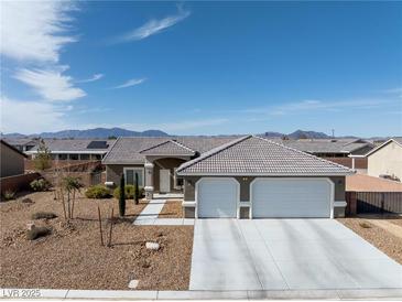 Charming single-story home featuring a three-car garage, desert landscaping, and a mountain view at 50 White Burch Ln, Pahrump, NV 89048