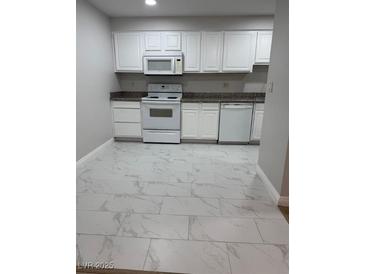Bright kitchen features white cabinetry, tile flooring, modern appliances, and granite countertops at 5241 River Glen Dr # 184, Las Vegas, NV 89103