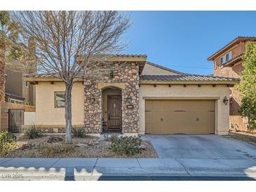 Charming single-story home featuring a stone facade, arched entry, and a two-car garage at 1049 Via Saint Lucia Pl, Henderson, NV 89011