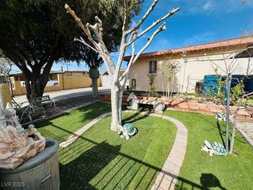 Landscaped front yard with lush artificial turf, decorative stone accents, and charming outdoor décor at 3601 Chevy Chase Ave, Las Vegas, NV 89110