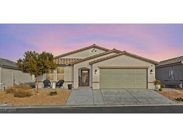 Charming single-story home featuring desert landscaping, a tile roof, and an attached two-car garage at 452 Triple Falls St, Indian Springs, NV 89018