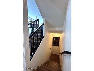 View of stairway with wooden steps and black handrail leading to the lower level and featuring a wall mirror at 8426 Sluman Ct, Las Vegas, NV 89128