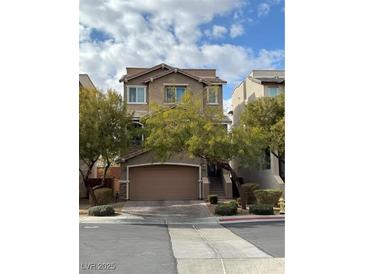 Two-story home with a large garage, manicured landscaping, and a neutral color palette at 10415 Scarpa St, Las Vegas, NV 89178