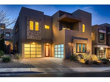 Modern two-story home featuring stone accents and a well-lit driveway, enhancing its curb appeal and contemporary design at 221 Errogie St, Henderson, NV 89012