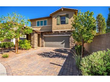 Charming two-story home with brick driveway, stone accents, lush trees, and a well-manicured lawn at 306 Dedication Ave, Henderson, NV 89011