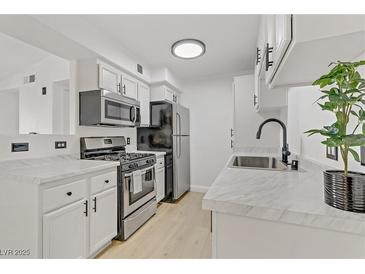 Bright kitchen features stainless steel appliances, light wood flooring and white cabinets with black hardware at 3318 N Decatur Blvd # 2007, Las Vegas, NV 89130