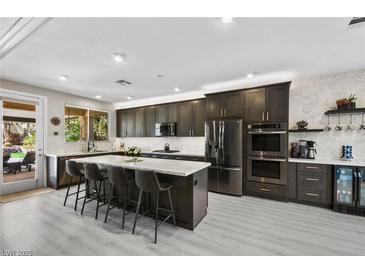 Modern kitchen featuring dark cabinets, stainless steel appliances, and a large center island with bar seating at 8145 Mountain Forest Ct, Las Vegas, NV 89129