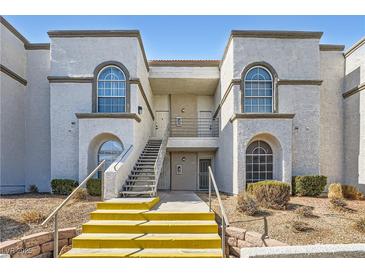 Exterior view of building with arched windows, tan stucco and yellow painted stairs at 3150 Soft Breezes Dr # 2022, Las Vegas, NV 89128