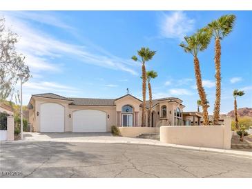 Elegant home featuring a three-car garage, desert landscaping, and a grand entrance with palm trees at 379 Turquoise Ct, Boulder City, NV 89005