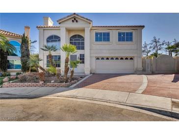 Elegant two-story home featuring a symmetrical facade, arched windows, and a brick driveway at 1 Rising Sun Ct, Henderson, NV 89074