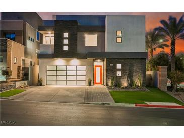 Modern two-story home with a glass garage door, orange front door, and drought-tolerant landscaping at 800 Loch Katrine Ave, Henderson, NV 89012