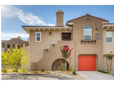 Charming townhouse with a red garage door, lush plants, and Mediterranean-style architecture at 11890 Tevare Ln # 1097, Las Vegas, NV 89138