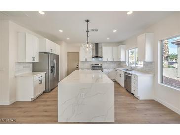 Bright kitchen with white cabinets, stainless steel appliances, and a large waterfall island at 2581 Terrytown Ave, Henderson, NV 89052