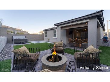 A beautiful backyard with a fire pit, seating area, hot tub and well manicured grass at 361 Black Turnstone Ct, Las Vegas, NV 89138