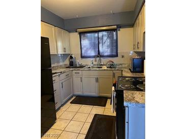 This kitchen features tile flooring, neutral cabinets, and granite countertops at 4200 Coran Ln, Las Vegas, NV 89108
